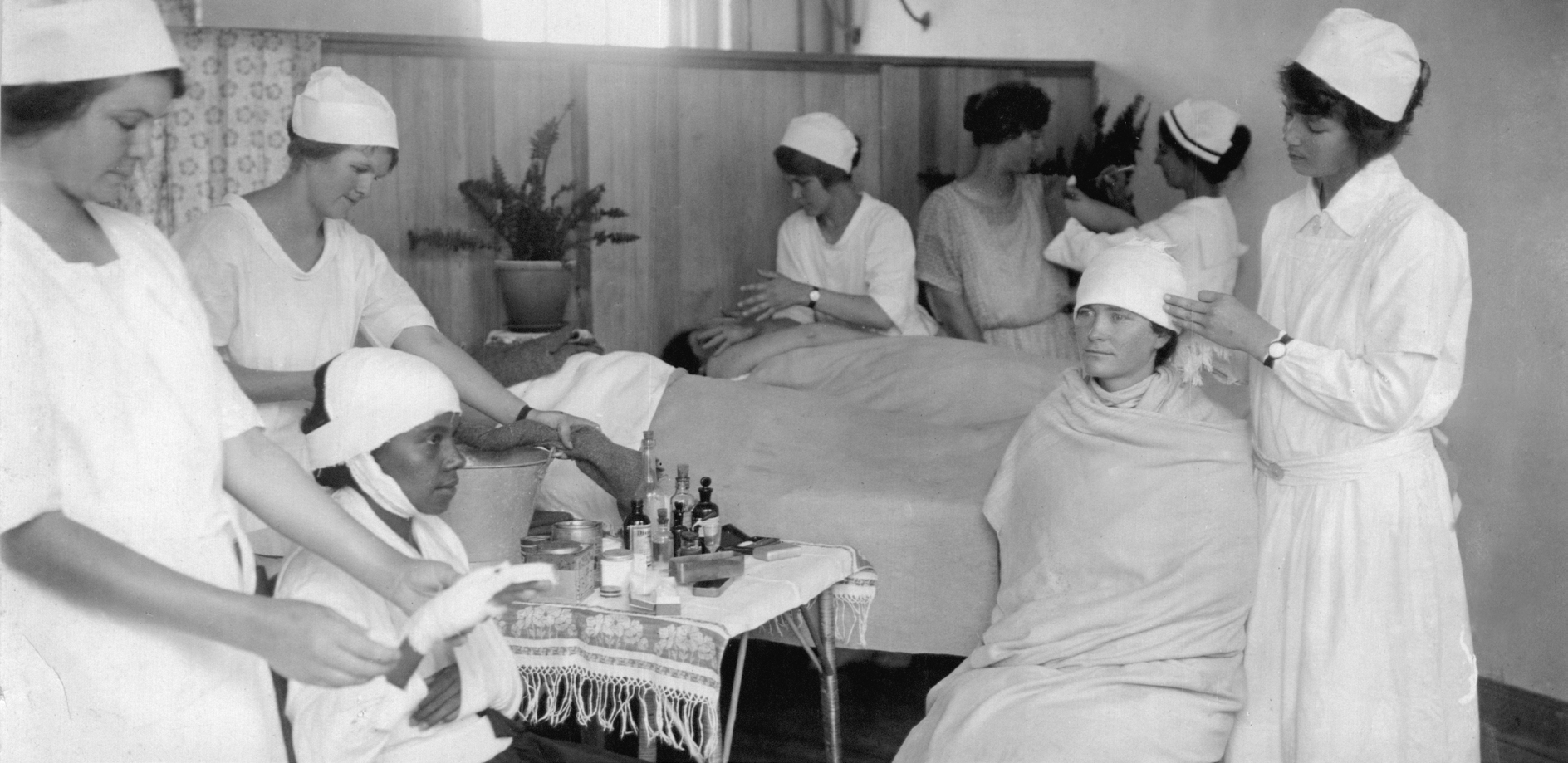 Grupo de estudantes de enfermagem realizando uma aula prática de primeiros socorros em 1925.