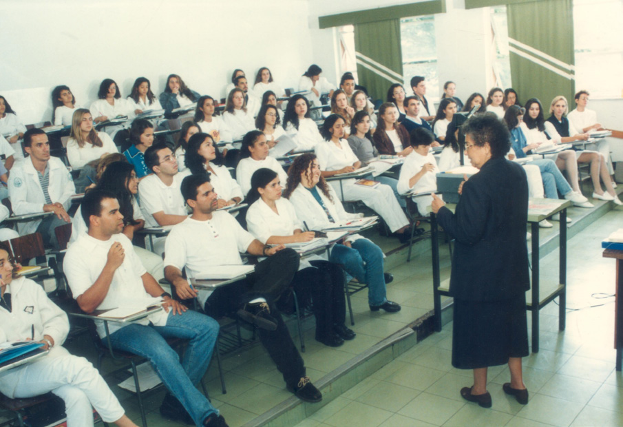 Professora diante de estudantes em uma sala de aula do curso de Enfermagem.